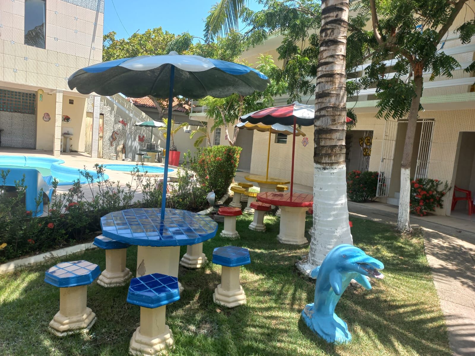 Mesas de mosaico coloridas com escultura de golfinho no jardim