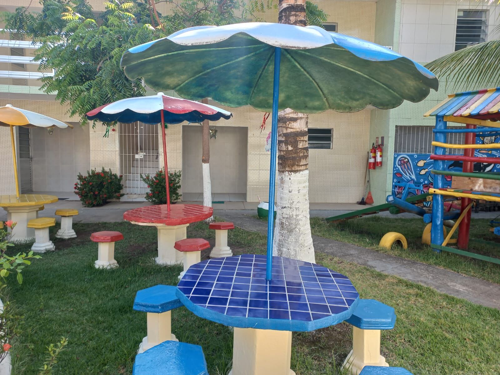 Mesa de mosaico azul sob os coqueiros no jardim