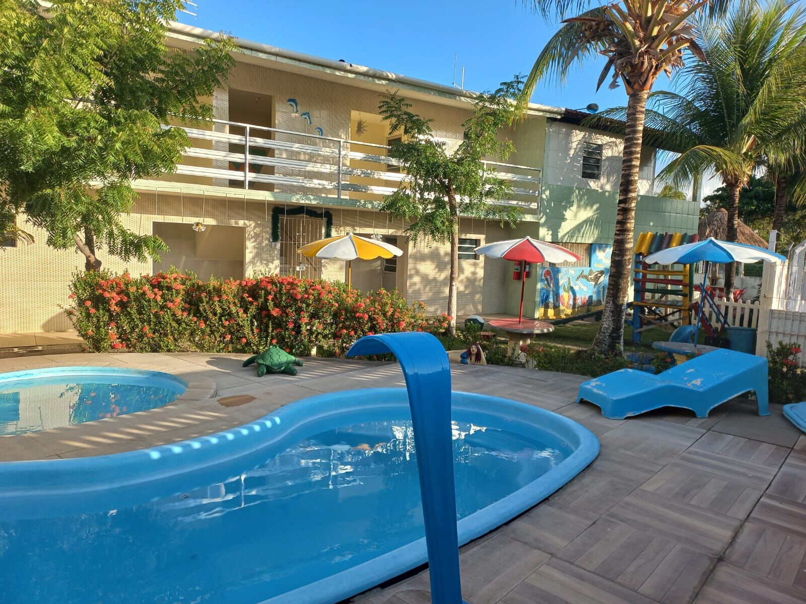 Piscina do Privê Ebenézer cercada por coqueiros, ao entardecer
