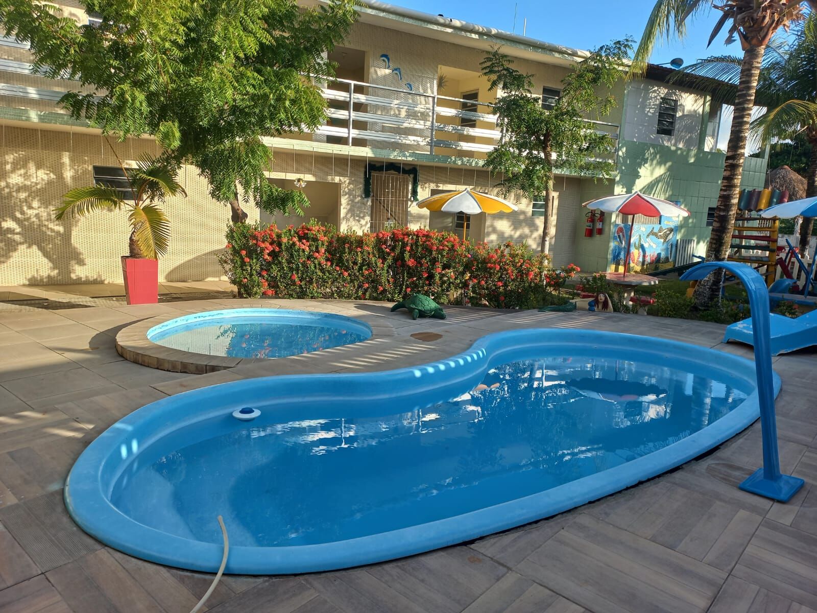 Piscina em formato de feijão com hidromassagem ao fundo